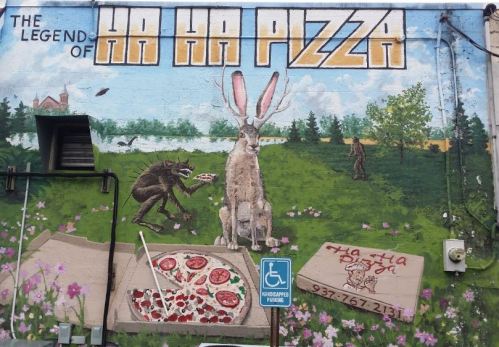 A colorful mural featuring a rabbit with long ears and a creature sharing pizza in a grassy landscape.