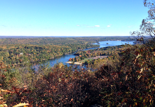 A scenic view of a river winding through colorful autumn foliage under a clear blue sky.