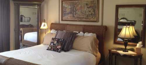 Cozy bedroom featuring a woven bed, decorative pillows, mirrors, and warm lighting.