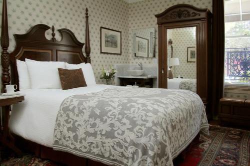 Cozy bedroom with a wooden bed, decorative quilt, and vintage furnishings, featuring a mirror and floral accents.