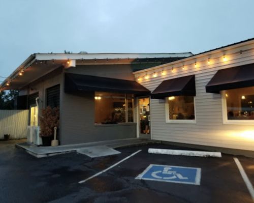 A cozy restaurant exterior with warm lights, awnings, and a designated handicap parking space.
