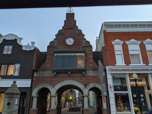 Historic brick building with a clock tower, arched entrance, and decorative windows, set against a twilight sky.