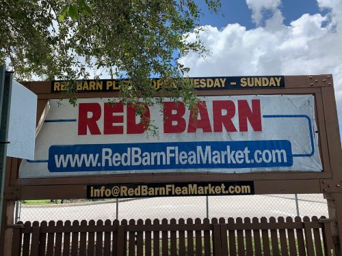 Sign for Red Barn Flea Market, open Wednesday to Sunday, with website and contact information displayed.