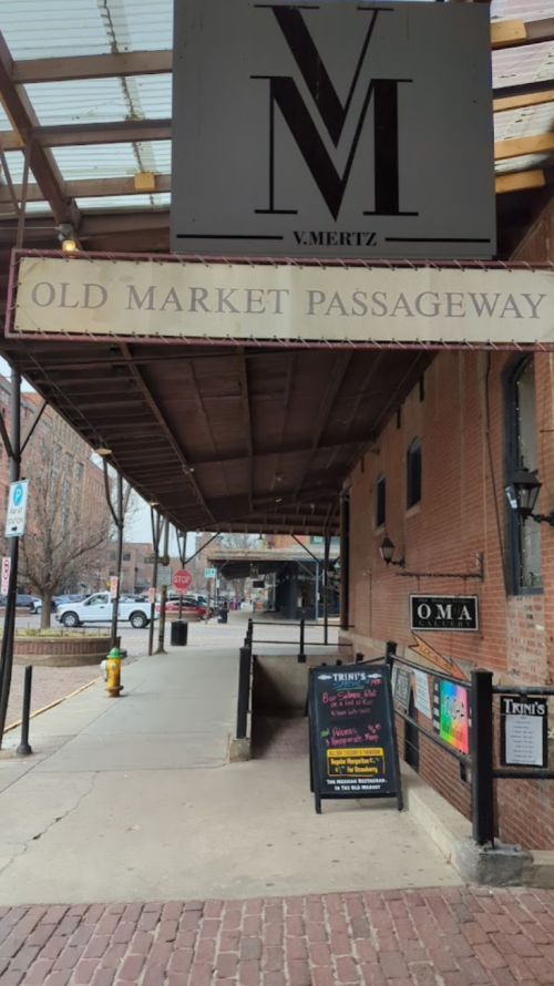 View of a covered walkway in a brick building, featuring signs for "Old Market Passageway" and nearby businesses.