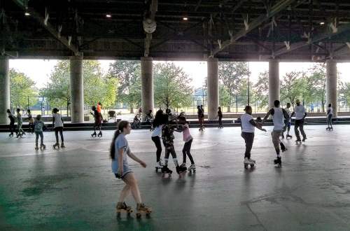 A lively roller skating rink with people of all ages skating and enjoying the activity under a spacious roof.