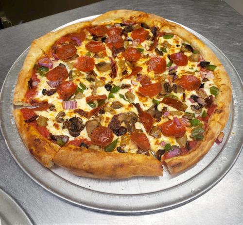 A freshly baked pizza topped with pepperoni, mushrooms, onions, and green peppers on a silver pizza tray.