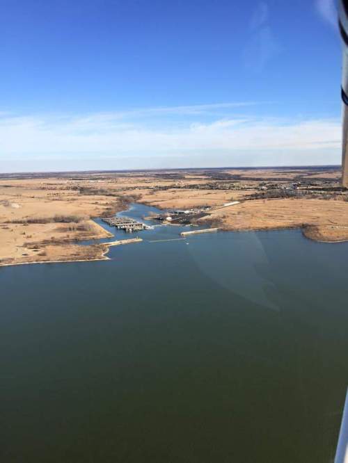 Aerial view of a river winding through a landscape of fields and water under a clear blue sky.