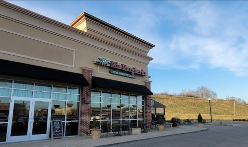 Exterior of Mia Margarita restaurant with large windows and outdoor seating, under a clear blue sky.