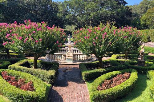 A beautifully landscaped garden featuring flowering trees, a fountain, and neatly trimmed hedges in a serene setting.