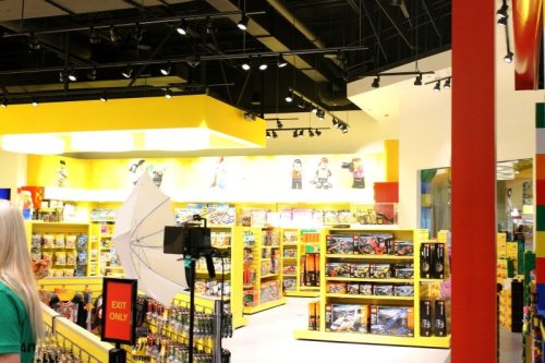 Brightly lit store interior with colorful shelves filled with toys and games, featuring a photo setup in the foreground.
