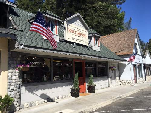 A charming storefront with a sign reading "ENCOMPASS," featuring American flags and flower pots outside.