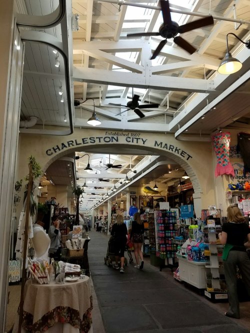 Interior view of Charleston City Market, featuring shops, stalls, and visitors under a bright, airy ceiling.