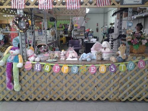 A festive display featuring stuffed animals and decorations with a "Happy Easter" banner at a market stall.