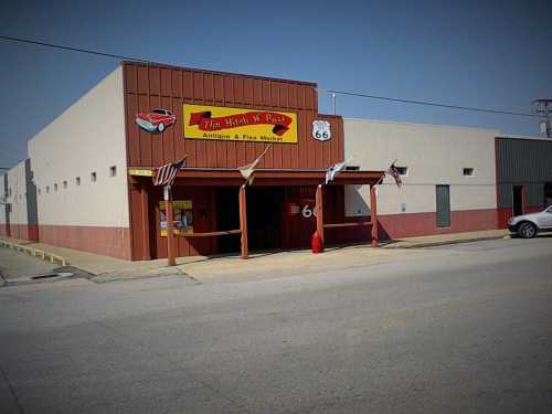 A storefront with a red and yellow sign reading "The Hippy's Place" on Route 66, featuring antique and flea market items.