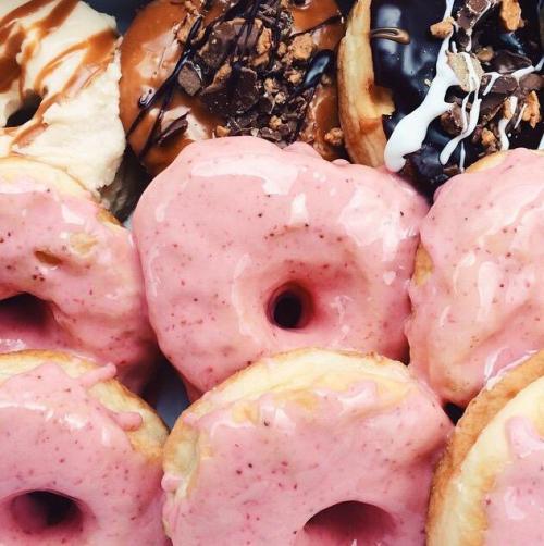 A variety of donuts, including glazed, chocolate, and pink frosted, arranged together in a colorful display.