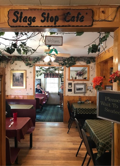 Interior of Stage Stop Café, featuring tables with green checkered tablecloths and a welcoming atmosphere.