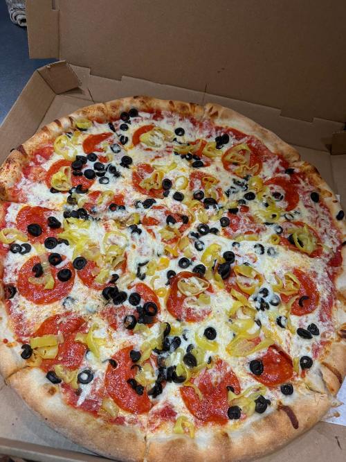A large pizza topped with pepperoni, black olives, and yellow peppers, in a pizza box.