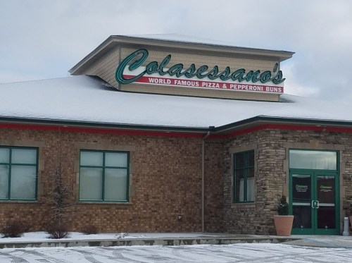 Sign for Colasessano's, featuring "World Famous Pizza & Pepperoni Buns," on a snowy day.