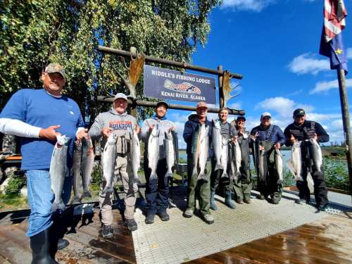 Group of eight anglers proudly holding their catch of salmon at Riddle's Fishing Lodge, Kenai River, Alaska.