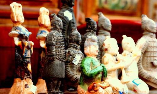 A collection of colorful ceramic figurines, including warriors and traditional characters, displayed on a wooden surface.