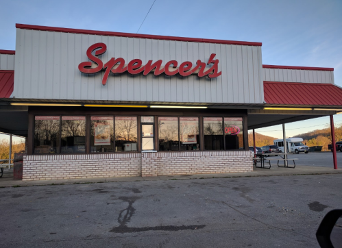 A storefront with the sign "Spencer's" in red letters, featuring large windows and a covered entrance.