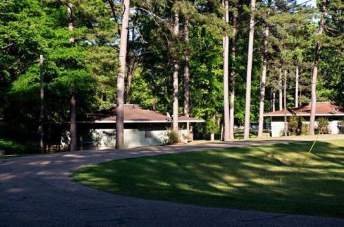 A winding road leads through a wooded area with modern buildings nestled among tall trees.