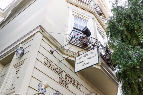 A corner view of the Union Street Inn, featuring a sign and a balcony with potted plants.