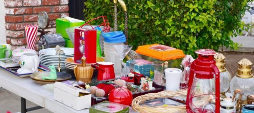 A table filled with various items for sale, including dishes, lanterns, toys, and decorative objects.