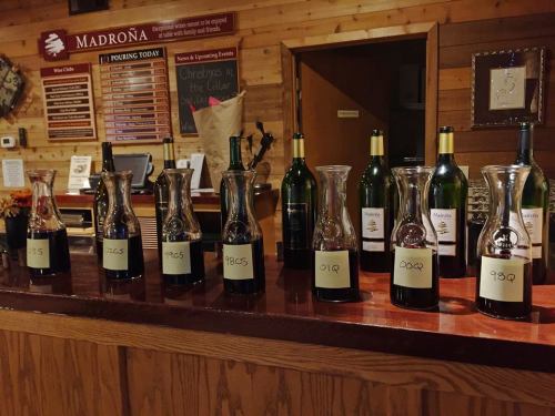 A wooden bar displaying various wine bottles and decanters, each labeled with different years.