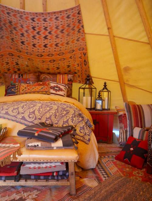 Cozy interior of a yurt with colorful textiles, a bed, lanterns, and decorative pillows. Warm and inviting atmosphere.