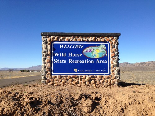 Welcome sign for Wild Horse State Recreation Area, featuring stone structure and clear blue sky in the background.