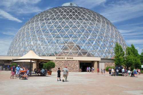 A large geodesic dome structure labeled "Desert Dome," with visitors walking around and enjoying the outdoor space.