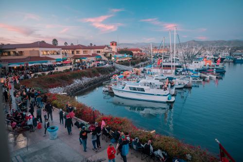 A vibrant marina at sunset, with boats docked and people enjoying the waterfront atmosphere.