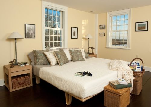 Cozy bedroom with a bed, decorative pillows, side tables, and large windows letting in natural light.