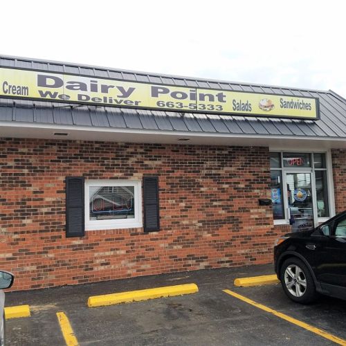 Exterior of Dairy Point, a brick building with a sign advertising ice cream, salads, and sandwiches. Open for business.