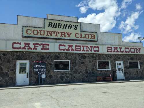 Sign for Bruno's Country Club featuring a café, casino, and saloon, with a stone facade and blue sky in the background.