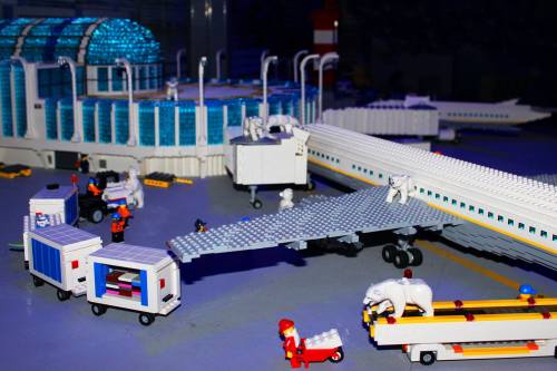 A colorful LEGO airport scene with an airplane, service vehicles, and mini-figures, including a polar bear on a cart.