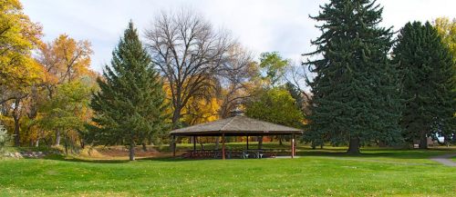 A park scene featuring a gazebo surrounded by trees with autumn foliage and a grassy area.