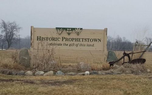 Sign for Historic Prophetstown, featuring text about celebrating the land, with a plow and stones in the foreground.