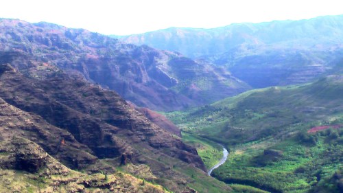 A scenic view of a lush valley surrounded by mountains, with a winding river flowing through the greenery.