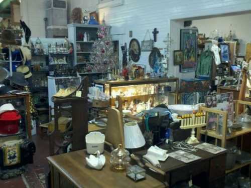 A cluttered antique shop filled with various vintage items, furniture, and decorative pieces.