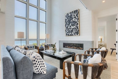 Modern living room with large windows, stylish furniture, and a sleek fireplace, overlooking a scenic view.