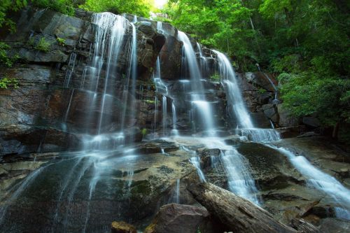 A serene waterfall cascading over rocky cliffs, surrounded by lush green trees and vibrant foliage.