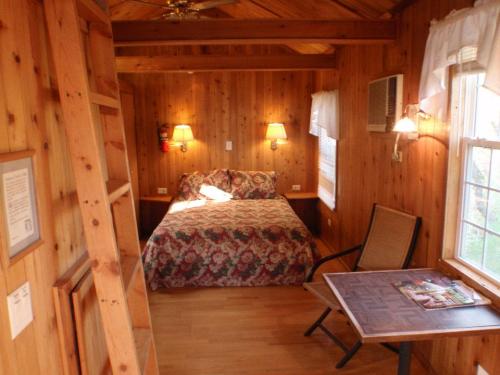 Cozy wooden cabin interior featuring a bed, chair, table, and air conditioning unit with warm lighting.
