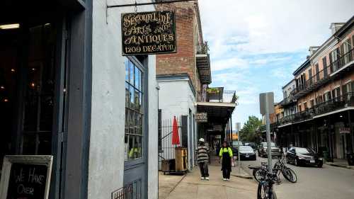 A street view of Decatur Street featuring antique shops, pedestrians, and parked bicycles under a cloudy sky.