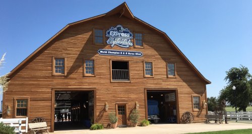 A large wooden barn with a sign reading "Express Livestock" and a clear blue sky in the background.