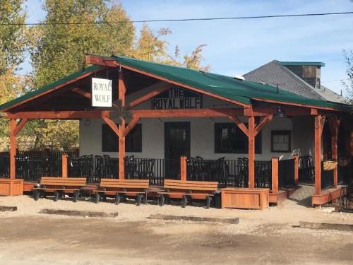 A rustic building with a green roof and outdoor seating, featuring a sign that reads "The Royal Wolf."