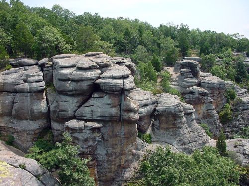 Rock formations surrounded by lush greenery under a clear sky.