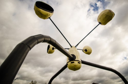 A whimsical, abstract sculpture with multiple rounded elements extending from a central base against a cloudy sky.