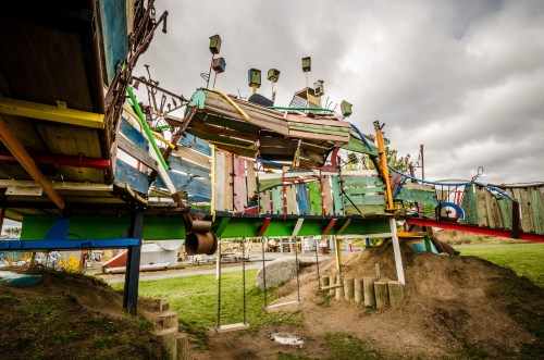 Colorful, whimsical playground structure made of various materials, set against a cloudy sky.